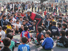 子ども達の真ん中に入って走り方のコツを話す川本監督。